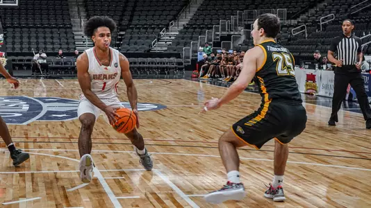 Mercer men's basketball player wearing a white jersey drives toward the basket holding the basketball in front of him