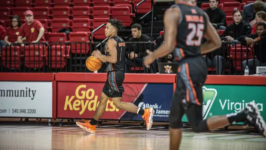 Kamar Robertson, in a black jersey, dribbling the basketball