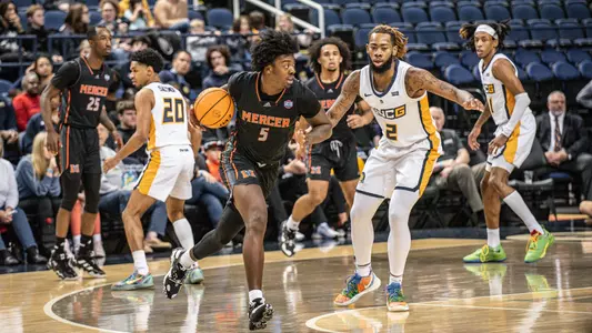 Jalyn McCreary, in a black jersey, dribbling the basketball while a defender, in a white jersey, guards him