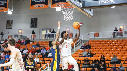 Jalyn McCreary reaching up to score a layup while a defender jumps with him