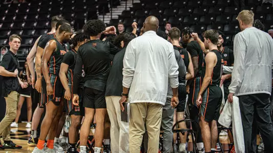 The men's basketball team in a huddle at a timeout