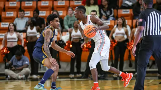 Shawn Walker Jr. holding the basketball with both hands while a defender stands in front of him