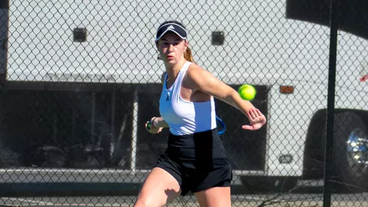 Mary Weston Courville in her swing with the racket behind her body about to hit a forehand shot