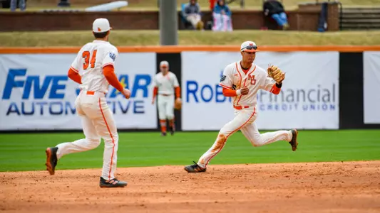 Bradley Frye catching a ball in the infield while Trevor Austin watches him