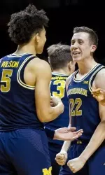 D.J. Wilson celebrates his OT-forcing triple with Duncan Robinson (22) and Zak Irvin