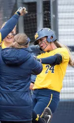 The Wolverines greet Tera Blanco (right) after her first home run Saturday