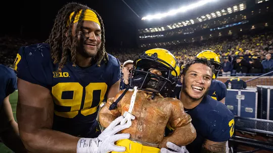 Mike Morris, left, and Blake Corum Carry the Paul Bunyan Trophy