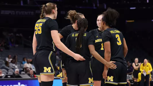 Women's basketball team huddle all blue road uniforms