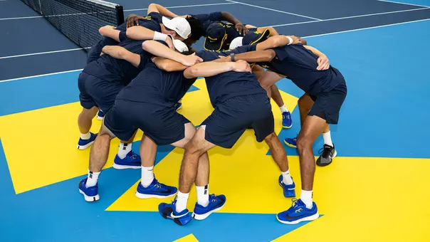 Men's tennis team huddle indoors