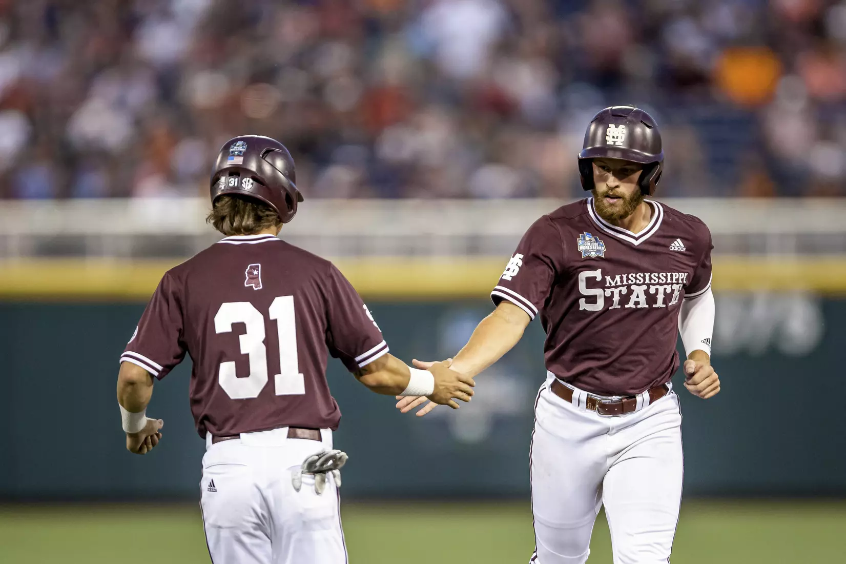 OMAHA, NE - June 22, 2021 - Mississippi State Infielder Tanner Leggett (#31) and Infielder Luke Hancock (#20) slap hands during the 2021 Mens College World Series game between the Mississippi State Bulldogs and the Virginia Cavaliers at TD Ameritrade Park in Omaha, NE. Photo By Austin Perryman