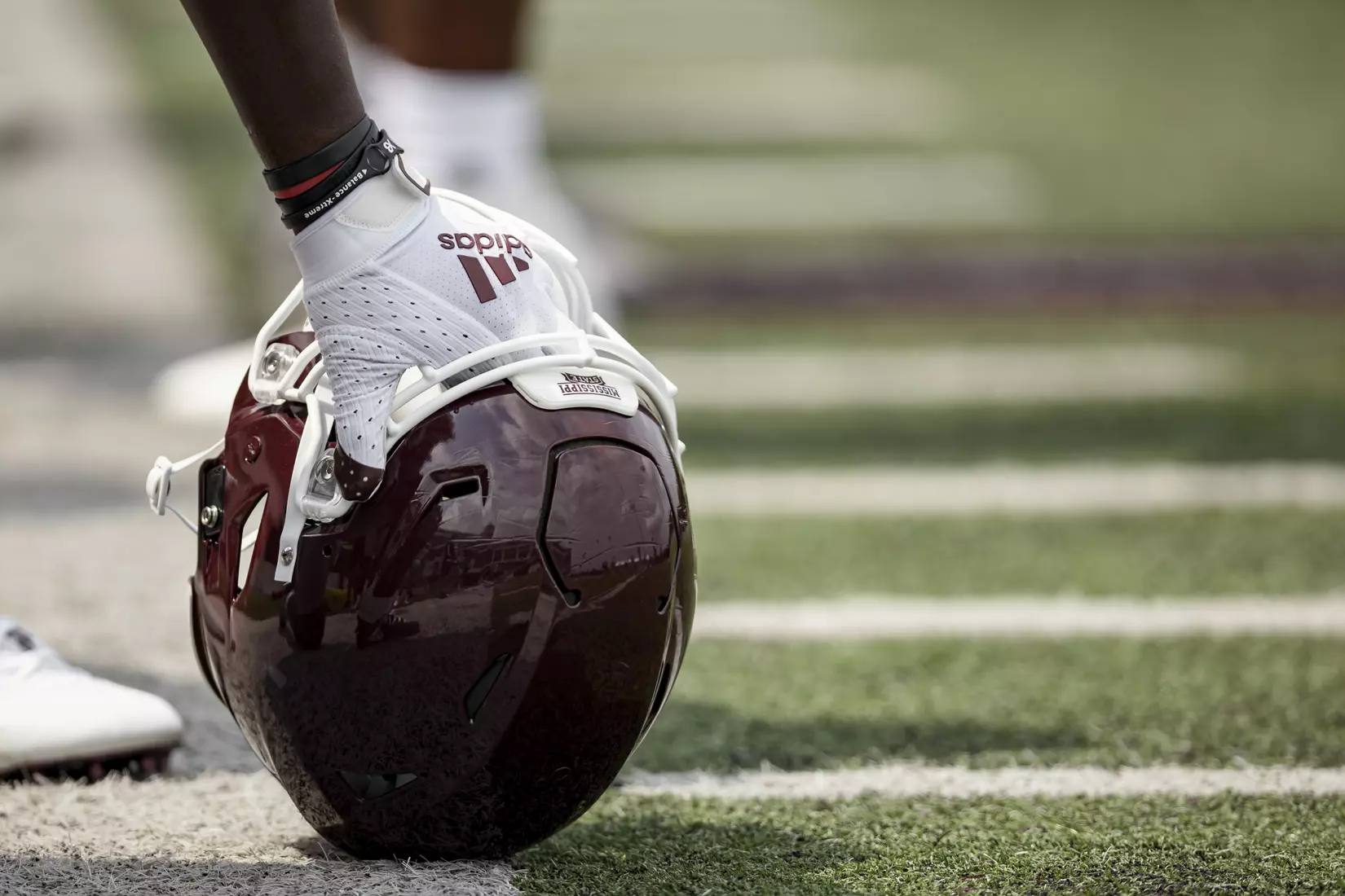 STARKVILLE, MS - August 06, 2021 - Adidas logo football glove holding a helmet during a training camp practice at the Leo Seal Jr. Football Complex at Mississippi State University in Starkville, MS. Photo By Austin Perryman