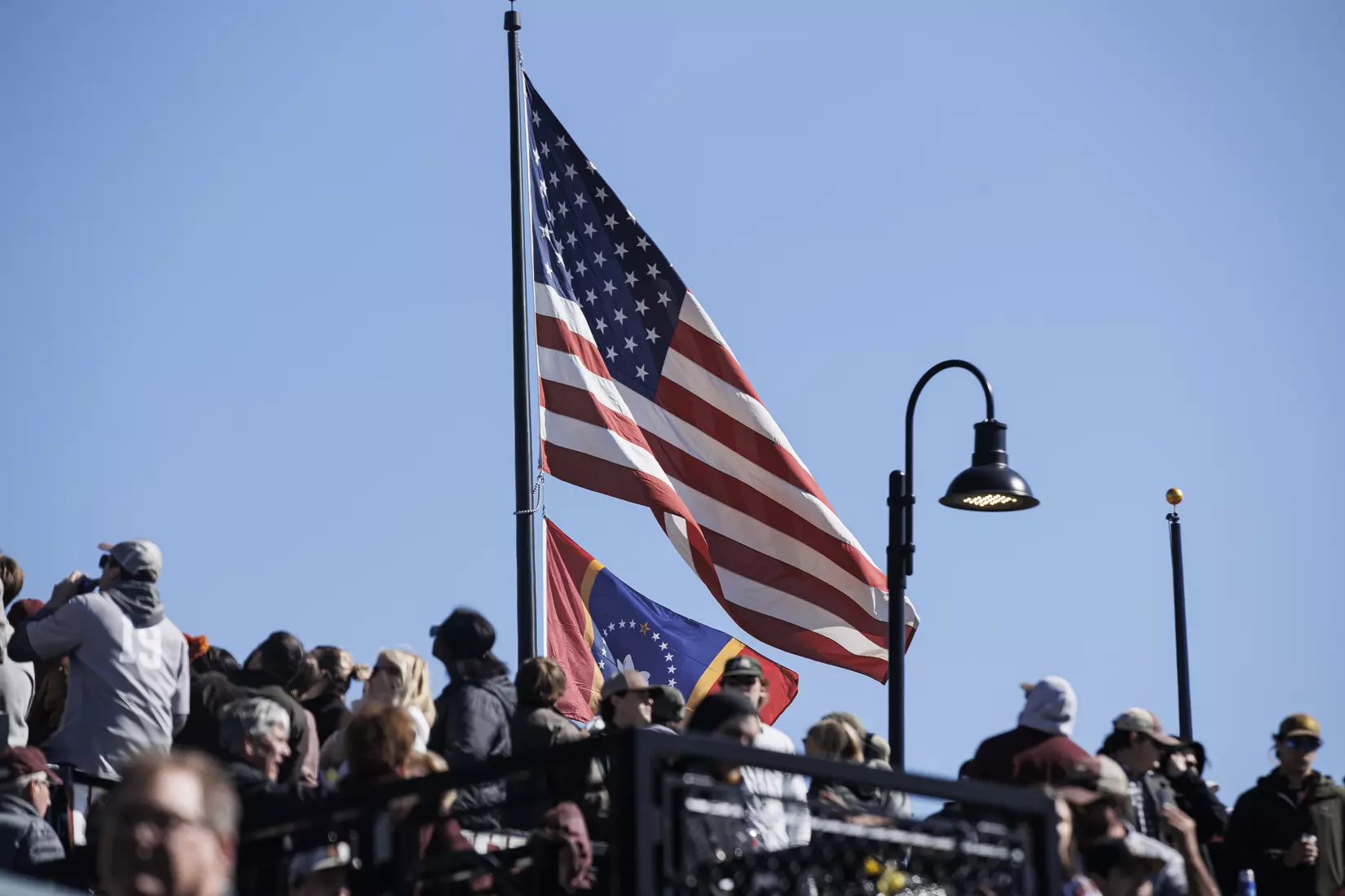 STARKVILLE, MS - February 18, 2022 - American Flag flowing in the wind above fans before the game between the Long Beach State Dirtbags and the Mississippi State Bulldogs at Dudy Noble Field at Polk-Dement Stadium in Starkville, MS. Photo By Kevin Snyder