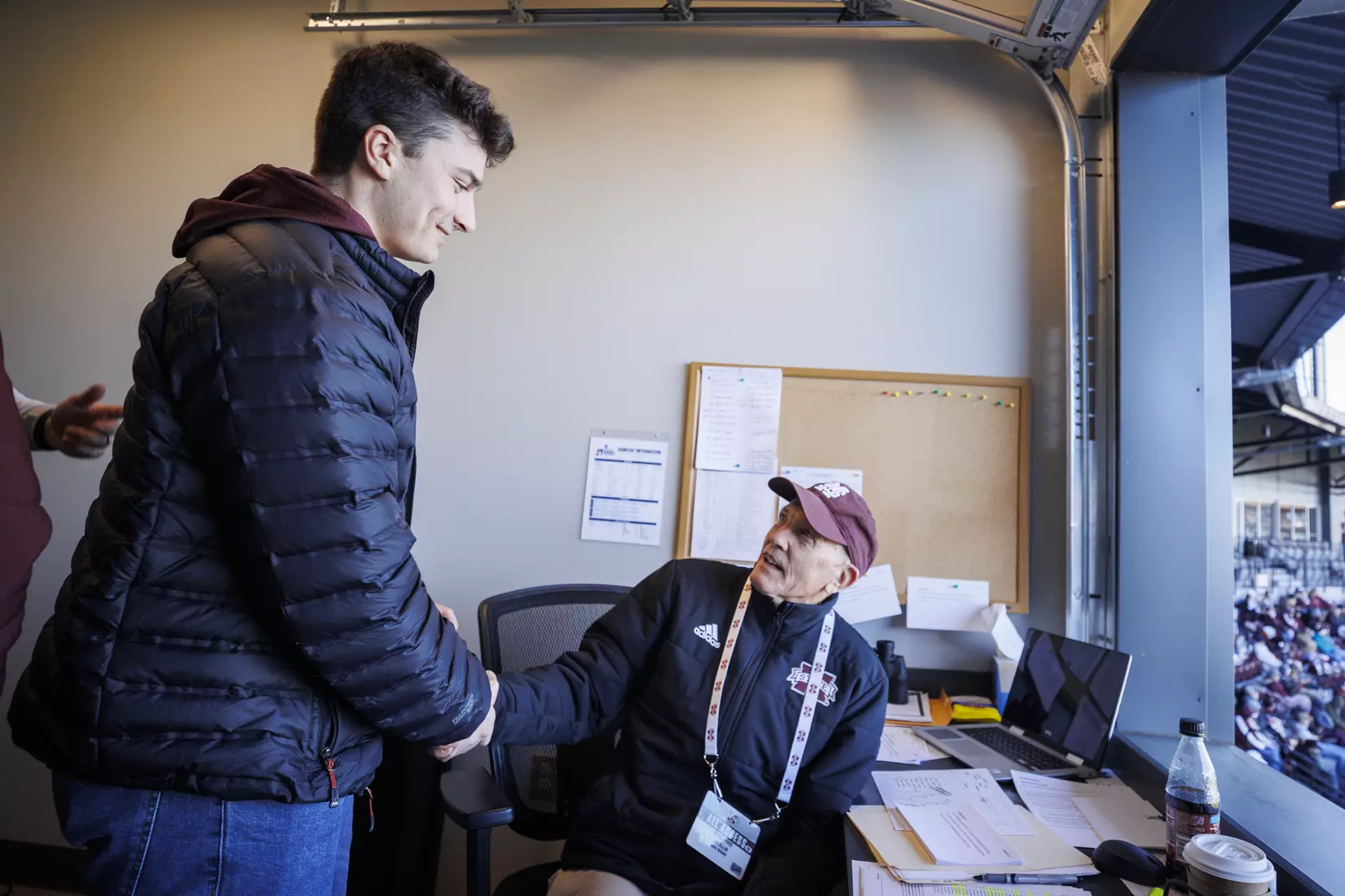 STARKVILLE, MS - February 18, 2022 - Former Mississippi State Infielder Justin Foscue shakes hands with Mississippi State Radio Broadcast Announcer Jim Ellis in the radio booth during the game between the Long Beach State Dirtbags and the Mississippi State Bulldogs at Dudy Noble Field at Polk-Dement Stadium in Starkville, MS. Photo By Kevin Snyder