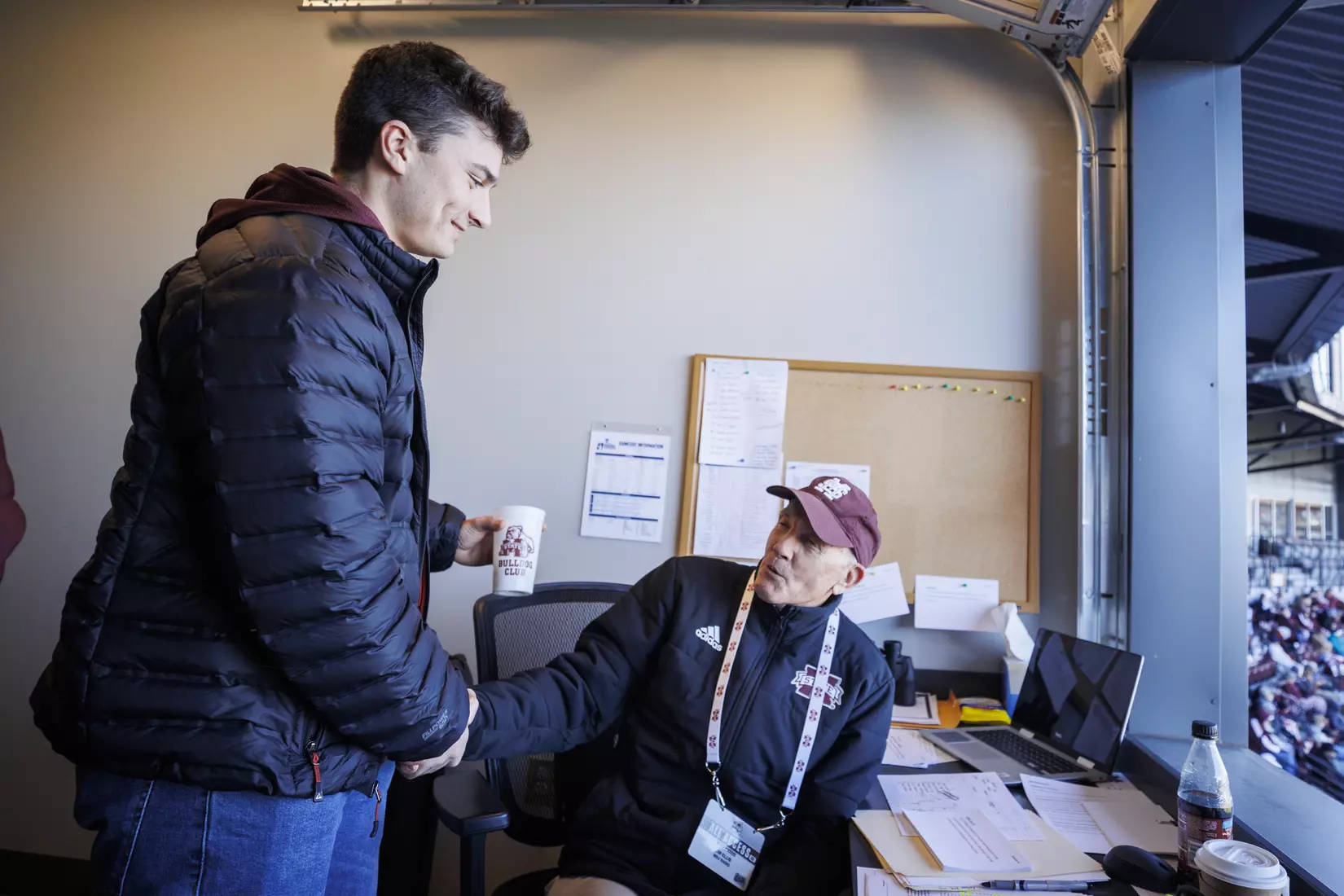 STARKVILLE, MS - February 18, 2022 - Former Mississippi State Infielder Justin Foscue shakes hands with Mississippi State Radio Broadcast Announcer Jim Ellis in the radio booth during the game between the Long Beach State Dirtbags and the Mississippi State Bulldogs at Dudy Noble Field at Polk-Dement Stadium in Starkville, MS. Photo By Kevin Snyder