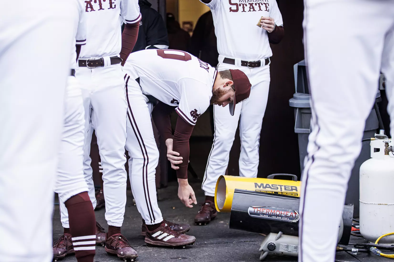 STARKVILLE, MS - February 26, 2022 - Mississippi State Infielder Luke Hancock (#20) warms his hands in the dugout before the game between the Northern Kentucky Norse and the Mississippi State Bulldogs at Dudy Noble Field at Polk-Dement Stadium in Starkville, MS. Photo By Kevin Snyder