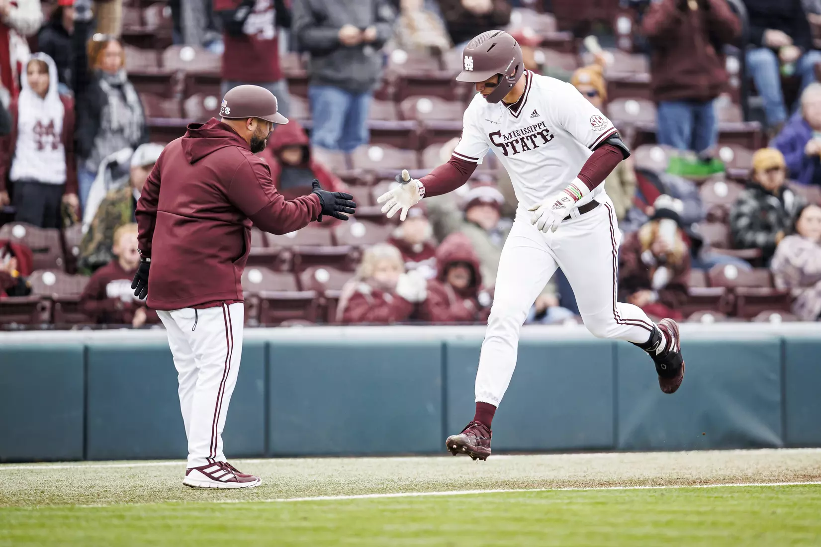 STARKVILLE, MS - February 26, 2022 - Mississippi State Outfielder Brad Cumbest (#33) shakes Assistant Coach Jake GautreauÕs hand after a home run during the game between the Northern Kentucky Norse and the Mississippi State Bulldogs at Dudy Noble Field at Polk-Dement Stadium in Starkville, MS. Photo By Kevin Snyder