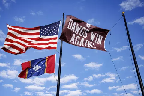 STARKVILLE, MS - February 20, 2022 - The Dawgs Win Again flag flies next to the American flag and the Mississippi flag after the game between the Long Beach State Dirtbags and the Mississippi State Bulldogs at Dudy Noble Field at Polk-Dement Stadium in Starkville, MS. Photo By Austin Perryman