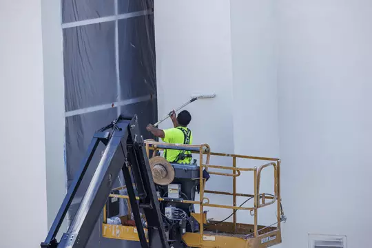 STARKVILLE, MS - July 05, 2022 - A construction worker applying a coat of paint to the wall during construction at Davis Wade Stadium at Scott Field in Starkville, MS. Photo By Kevin Snyder