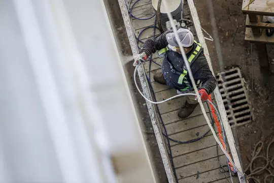 STARKVILLE, MS - July 05, 2022 - A construction worker sprays a coat of paint onto the railings during construction at Davis Wade Stadium at Scott Field in Starkville, MS. Photo By Kevin Snyder