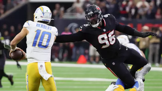 Jan 11, 2025; Houston, Texas, USA; Los Angeles Chargers quarterback Justin Herbert (10) is defended by Houston Texans defensive end Denico Autry (96) in the second quarter in an AFC wild card game at NRG Stadium. Mandatory Credit: Thomas Shea-Imagn Images