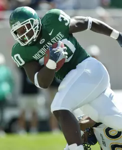 Michigan State's Jehuu Caulcrick scores a first-quarter touchdown over Kent State's Derico Murray. (AP Photo/Al Goldis)