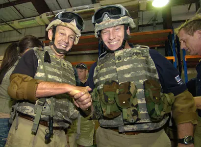Tom Izzo and South Carolina basketball coach Dave Odom wear helmets and body armor as they take part in a training exercise to escape from an overturned Humvee at Camp Arifjan, May 27, 2006.