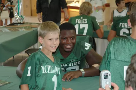 Running back Jehuu Caulcrick poses for a photo with this young fan during the fifth-annual Meet The Spartans event at Meridian Mall in Okemos.