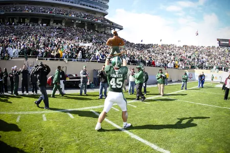 Andrew Hawken holds up the Paul Bunyan Trophy after MSU's 26-20 overtime win over Michigan.