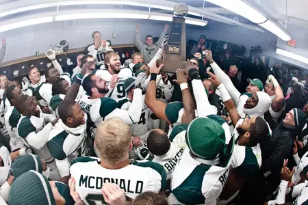 The Spartans hold up the 2010 Big Ten Championship trophy in the locker room after the win over Penn State.