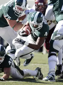Michigan State's Edwin Baker (4) dives into the end zone for a touchdown during the second quarter of an NCAA college football game against Minnesota, Saturday, Nov. 6, 2010, in East Lansing, Mich. Also seen are Michigan State's Nick Bendzuck (42) and Jared McGaha (75) and Minnesota's Ryan Grant. (AP Photo/Al Goldis)