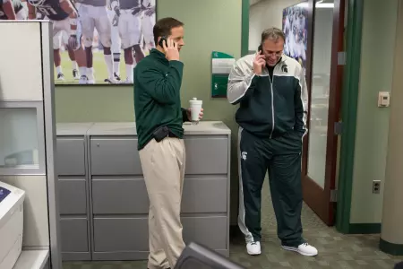 Brad Salem and Pat Narduzzi work their cell phones during Signing Day.