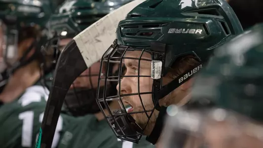 DETROIT, MI - FEBRUARY 11: Justin Jallen #12 of the Michigan State Spartans watches the action from the bench against the Michigan Wolverines during the first period of an NCAA MenÕs college hockey Dual in the D game at Little Caesars Arena on February 11, 2023 in Detroit, Michigan. The Wolverines defeated the Spartans 4-3 in O.T. (Photo by Dave Reginek/Getty Images) *** Local Caption *** Justin Jallen