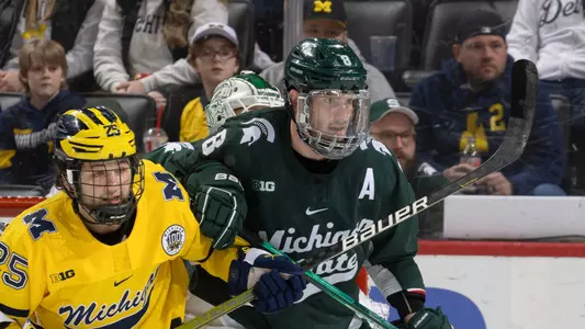 DETROIT, MI - FEBRUARY 11: Cole Krygier #8 of the Michigan State Spartans battles in front of the net with Dylan Duke #25 of the Michigan Wolverines during the first period of an NCAA MenÕs college hockey Dual in the D game at Little Caesars Arena on February 11, 2023 in Detroit, Michigan. The Wolverines defeated the Spartans 4-3 in O.T. (Photo by Dave Reginek/Getty Images) *** Local Caption *** Cole Krygier; Dylan Duke