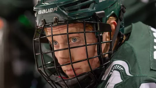 DETROIT, MI - FEBRUARY 11: Daniel Russell #20 of the Michigan State Spartans watches the action from the bench against the Michigan Wolverines during the first period of an NCAA MenÕs college hockey Dual in the D game at Little Caesars Arena on February 11, 2023 in Detroit, Michigan. The Wolverines defeated the Spartans 4-3 in O.T. (Photo by Dave Reginek/Getty Images) *** Local Caption *** Daniel Russell