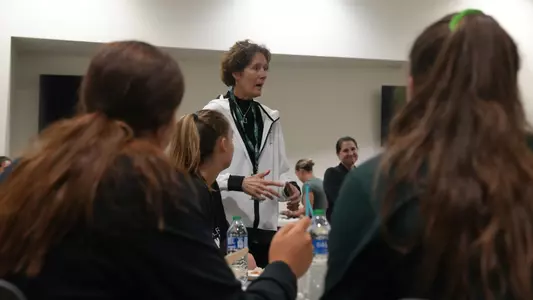 Kathy DeBoer '78 speaks to the volleyball team pre-game in 2023