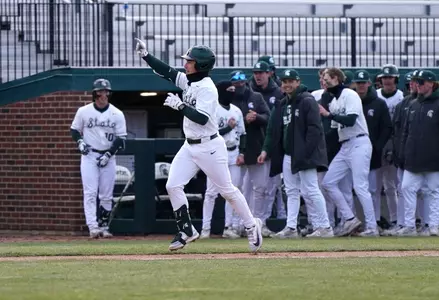 Ryan McKay celebrates home run, while his teammates celebrate in the dugout