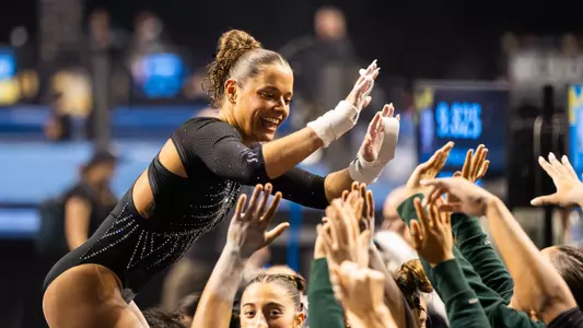 Sage Kellerman celebrates with the team after finishing a bar routine