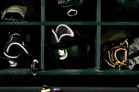 MSU baseball Spartan head batting helmet in dugout rack.
