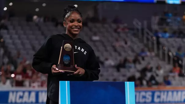 Nikki Smith stands with a trophy at the awards ceremony of the 2026 NCAA Gymnastics Championships