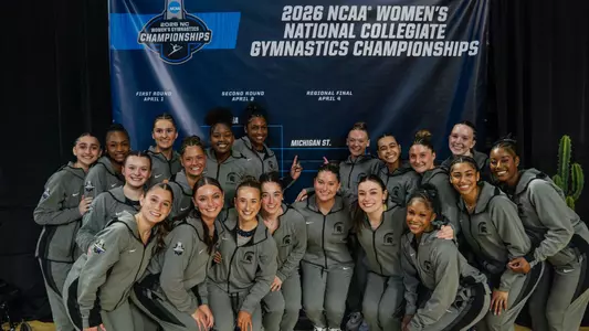 Gymnastics team in front of bracket after advancing at NCAA Tempe Regional