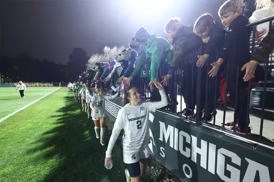 Women' Soccer high fiving fans