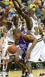 Johnnie Parker and Tajudeen Soyoye clamp down on Kansas' Ashante Johnson underneath the basket.