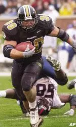 Missouri running back T.J. Leon pushes Kansas' Nick Reid, aside as he heads towards the endzone for his first touchdown of the day Saturday against Kansas.