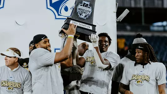 Chris mcClellan, Zion Young and Toriano Pride Jr. hold up the Music City Bowl trophy in 2024