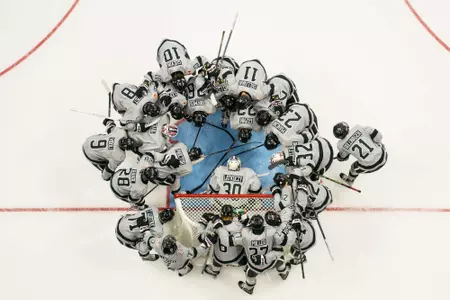 Players surround the goaltender before a game
