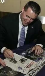 Head coach Pat Fitzgerald shows off his picture in an old sports magazine while signing autographs during the Big Ten's Kickoff Luncheon Wednesday. (AP Photo/Jerry Lai)