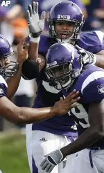 Omar Conteh, right, celebrates with teammates Corey Wootton, top, and Kevin Mitchell after scoring his first touchdown against Michigan. (AP Photo/Nam Y. Huh)