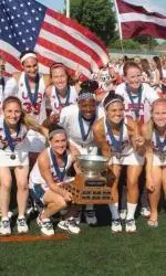 Team captain and former NU player and coach Lindsey Munday (kneeling, holding trophy) celebrates the U.S.' World Cup championship with her teammates. (Photo courtesy U.S. Lacrosse)
