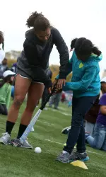 Isabel Flens shows a Field Day participant how to play field hockey.