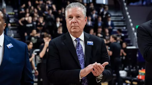 Northwestern Men's Basketball Assistant Coach Brian James stands and claps during the national anthem.